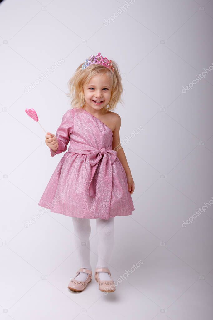 beautiful little blonde girl posing with a heart shaped Lollipop 