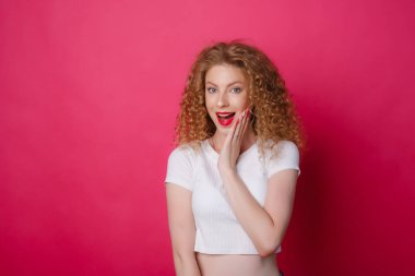 duygusal genç kadın pembe arka planda poz veriyor. Yüz ifadeleri yapıyor.