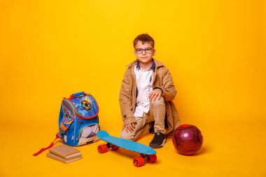 Sırt çantası ve sarı arka planda kitapları olan sevimli bir çocuğun portresi.