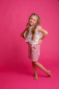Stüdyoda pembeye karşı poz veren zarif küçük kız