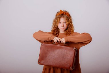 Gri arka planda bavulu olan güzel kız.