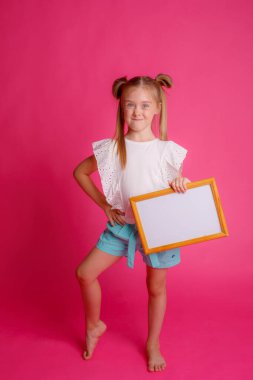 Boş bir çerçeve tutan bir kızın portresi, pembe bir arka planda, metin için yer 