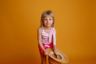 Yazlık kıyafetleri ve hasır şapkası olan küçük sarışın bir kız. 