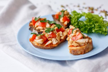 Beyaz tabakta somon, domates ve fesleğenli bruschetta.