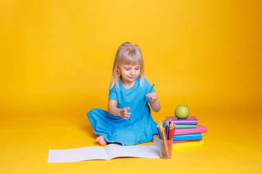 Okul öncesi eğitim kavramı, kitap yığını ve elma ile turuncu arka plan