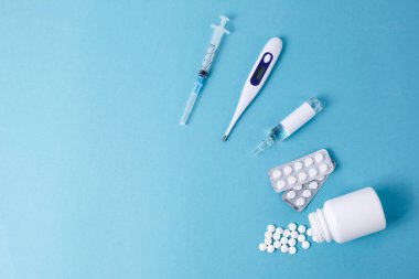 Haplar mavi arka planda şırınga termometresinden dökülüyor. Virüs koruma konsepti. Düz konum, üst görünüm, kopyalama alanı