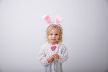 Beyaz arka planda elinde lolipop tutan tavşan kulaklı şirin bir kızın portresi. Paskalya konsepti