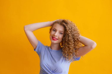 Stüdyoda turuncu arka planda poz veren güzel kızıl kadın.