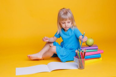 Okul öncesi eğitim kavramı, kitap yığını ve elma ile turuncu arka plan