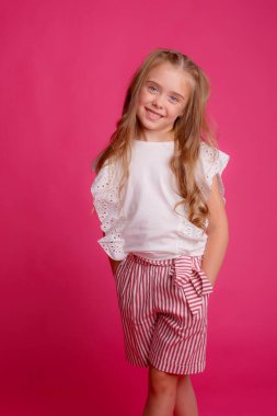 Stüdyoda pembeye karşı poz veren zarif küçük kız