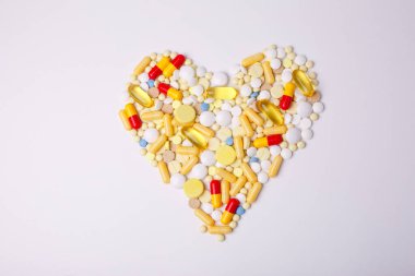 haplar ve kapsüller beyaz arka planda kalbi farklı renklerde şekillendirir.