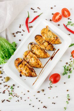 Kızarmış tavuk göğsü, sebzeli ve beyaz tabakta baharatlı.