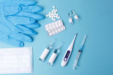 Haplar mavi arka planda şırınga termometresinden dökülüyor. Virüs koruma konsepti. Düz konum, üst görünüm, kopyalama alanı