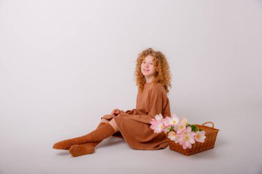 Güzel kızıl saçlı kız elinde bir buket bahar pembe çiçeğiyle sepette