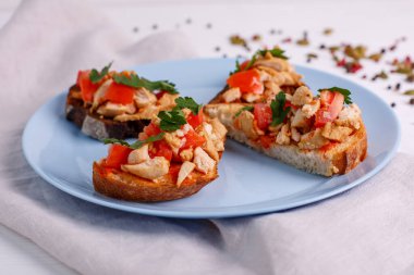 Beyaz tabakta somon, domates ve fesleğenli bruschetta.