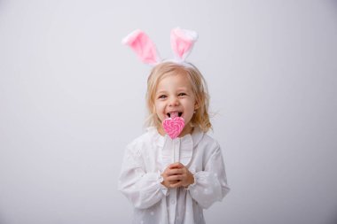 Beyaz arka planda elinde lolipop tutan tavşan kulaklı şirin bir kızın portresi. Paskalya konsepti