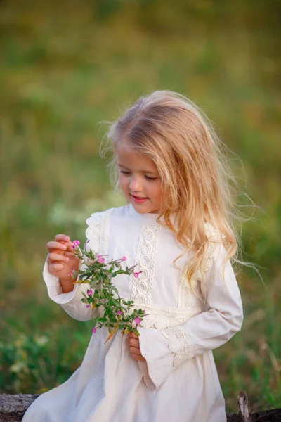 美しい女の子が花と一緒に畑にポーズ — ストック写真