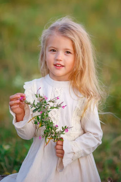 美しい女の子が花と一緒に畑にポーズ — ストック写真