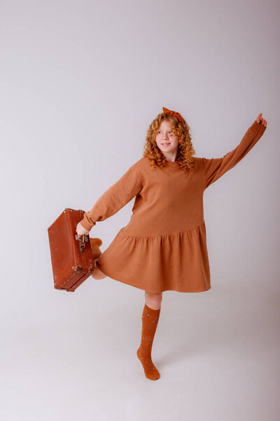 teenager girl posing in studio with suitcase.