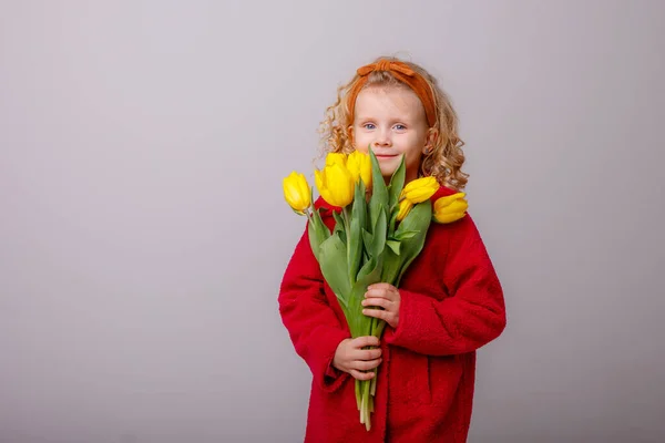 Bir Çocuk Sarışın Bir Kız Gri Arka Planda Sarı Laleler — Stok fotoğraf