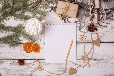 Boş Noel Baba listesi ve ahşap arka planda Noel süslemesi olan düz bir kompozisyon.