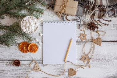 Boş Noel Baba listesi ve ahşap arka planda Noel süslemesi olan düz bir kompozisyon.