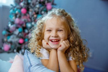 Noel ağacının yanında küçük bir kız yatağında yatıyor.  