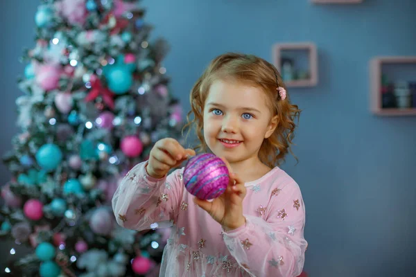 Una Bambina Vicino All Albero Natale Tiene Una Palla Natale — Foto Stock