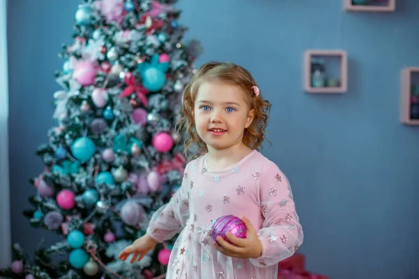 Una Bambina Vicino All Albero Natale Tiene Una Palla Natale — Foto Stock