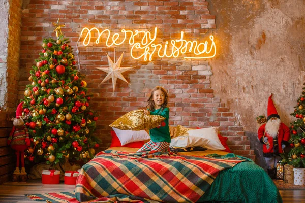 little girl Asian girl in her pajamas in the bedroom messing around on the cushions, Christmas, new year