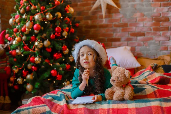 Little Asian Girl Pajamas Christmas Tree Writes Letter Santa Claus — Stock Photo, Image