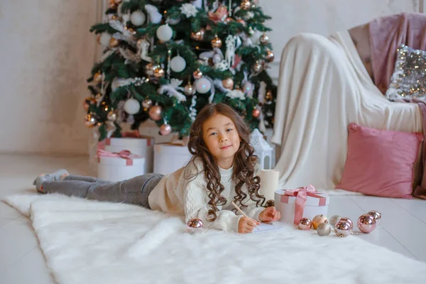 Little Asian Girl Writes Letter Santa Claus Christmas Tree Smiles — Stock Photo, Image