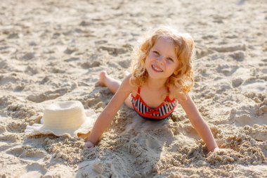 Küçük kız kumsalda yatıyor yaz mevsiminde