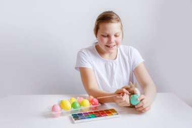 Küçük kız Paskalya yumurtalarını paskalya tavşanıyla boyuyor.