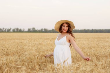 Hasır şapkalı hamile kadın buğday tarlasında