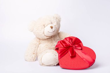 Kalp şeklinde sevgililer günü kutusuna sahip oyuncak ayı beyaz arka planda izole edilmiş.