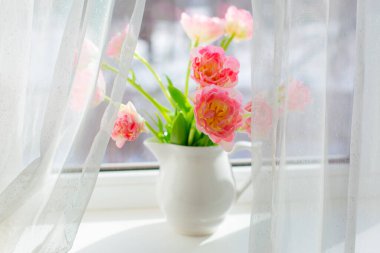 Pencerede pembe lalelerden bir vazo