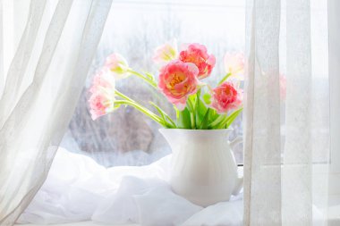 Pencerede pembe lalelerden bir vazo