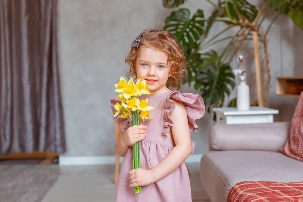 Klein Schattig Meisje Houdt Een Boeket Van Narcissen Thuis — Stockfoto