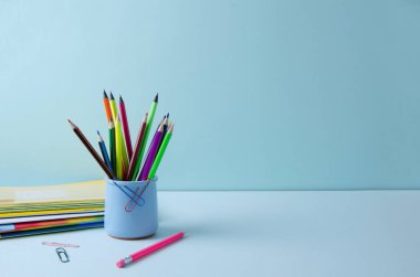 Mavi arka plandaki mavi bardakta kalemler farklıdır. Okula dönüş kavramı, seçici odaklanma, kopyalama alanı