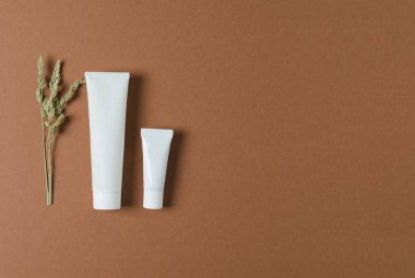 Yüzü, boynu, gözü, doğal bileşenleri olan beyaz plastik bir tüp. Kahverengi bir arka planda, düz ve düz bir düzlemde.