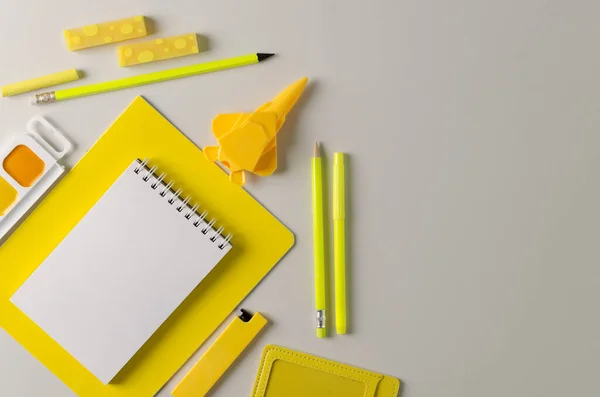 Back to school. The trend is yellow on grey. School stationery on a gray background. Pencils, erasers, notebooks, paints, sharpener plane - goods for the office yellow color.