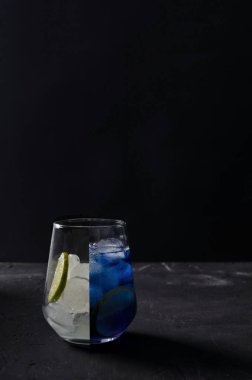 A creative shot of a cold blue cocktail. Half a glass of ice, the other half a blue cocktail.