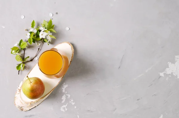 Pear juice in a glass and pear on a wooden tray and a concrete background, flat layout, copying space