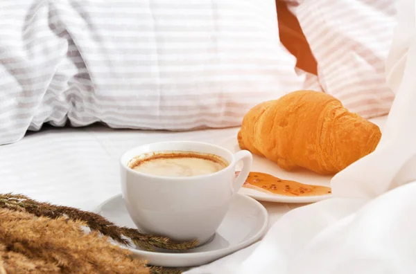 A cup of coffee with croissants in bed. The concept of morning coffee in bed.