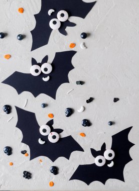 Cadılar Bayramı 'nda. Dekoratif komik yarasalar. Bej arkaplana serpiştirilmiş şekerlemeler, kopyalama metni, seçici odaklanma