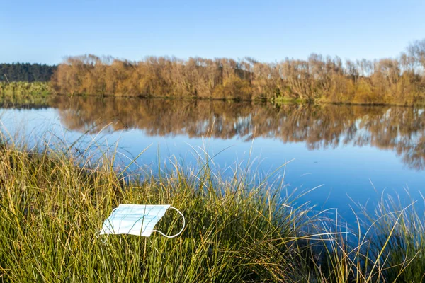 きれいな川のそばの草の上に残されたマスク — ストック写真
