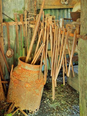 Eski süt kutusu ve biraz paslanmış bir demirci aleti koleksiyonu.