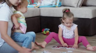 Çocukluk, oyunlar, yetiştirme ve geliştirme konsepti. Küçük çocukların genel planı. Erkek kardeş ve kız kardeş ile anne çocuk oyun odasında bulmaca çözer. Kardeşlerin karantinadaki evleri eğlencelidir.