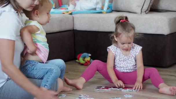 Kindheit, Spiele, Erziehung und Entwicklungskonzept - allgemeiner Plan der kleinen Kinder Junge Bruder und Mädchen Schwester mit Mama macht Rätsel im Kinderspielzimmer. Geschwister haben Spaß zu Hause in Quarantäne — Stockvideo